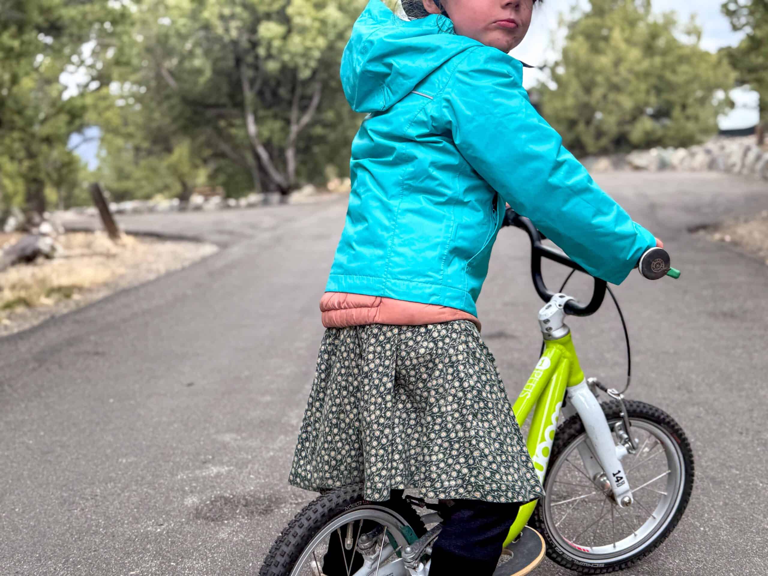 Young child riding green balance bike on outdoor path