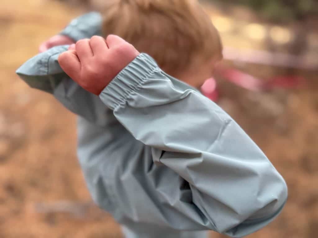 Young redhead child in gray rain jacket outdoors