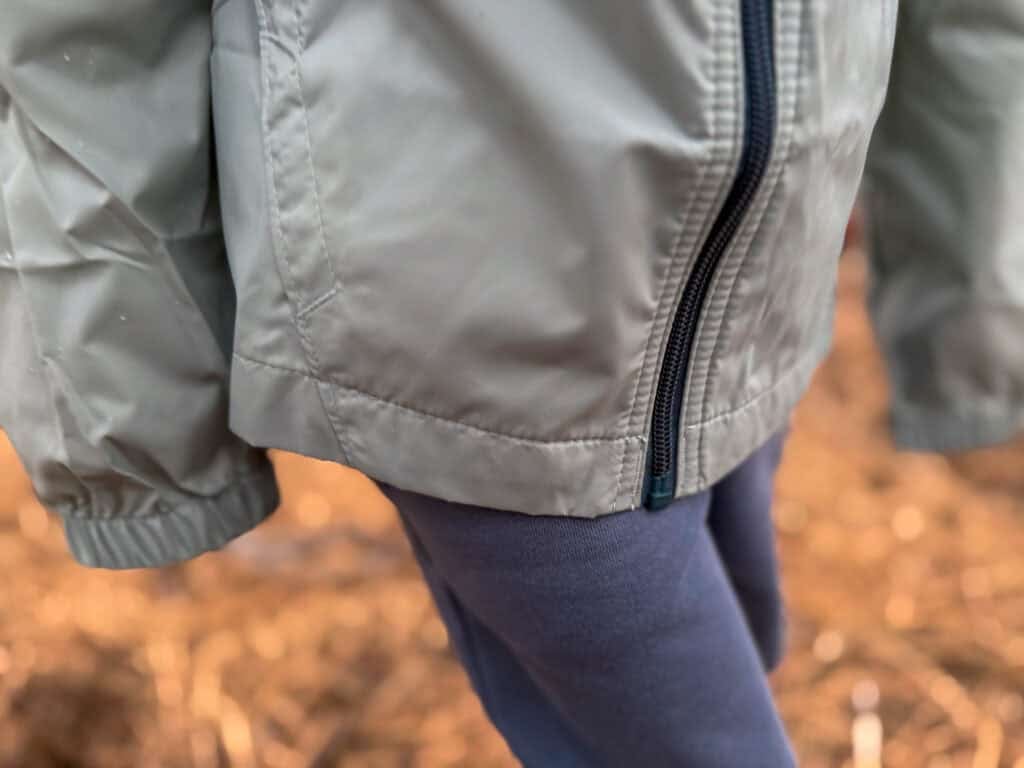 Close-up of gray zip-up jacket over navy blue leggings
