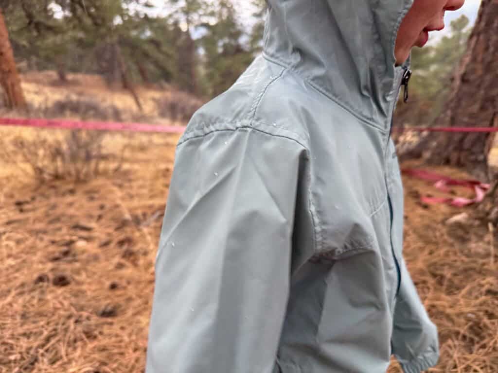 Light blue rain jacket with water droplets in forest