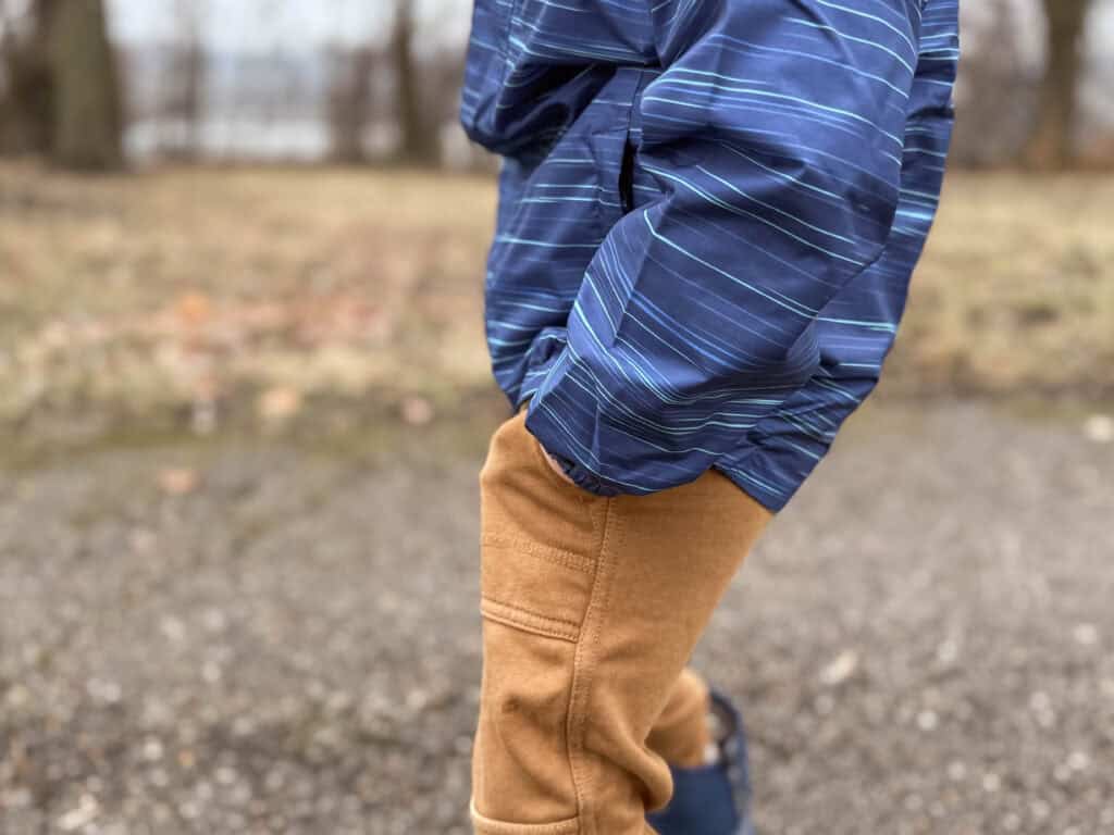 Child in blue striped jacket and tan pants outdoors
