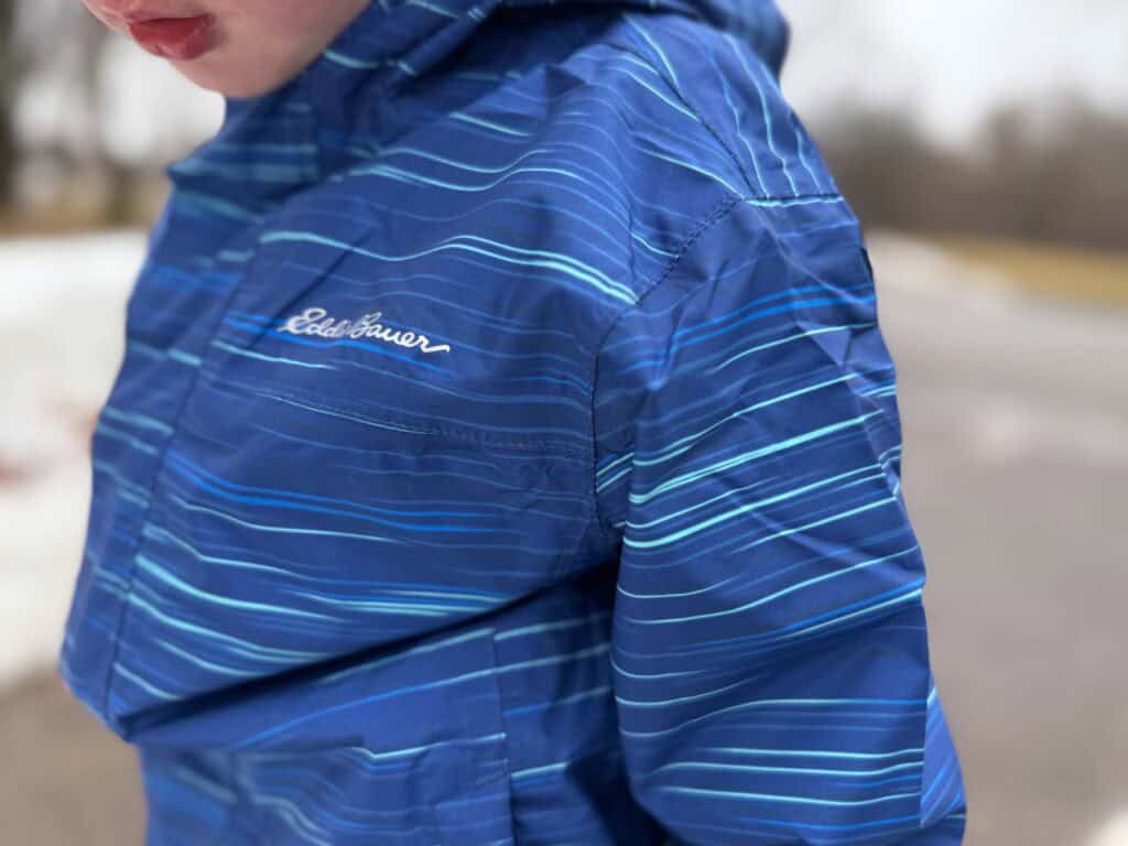 Child wearing blue striped Eddie Bauer winter jacket outdoors