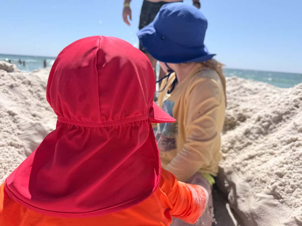 Two young children playing in sand at sunny beach