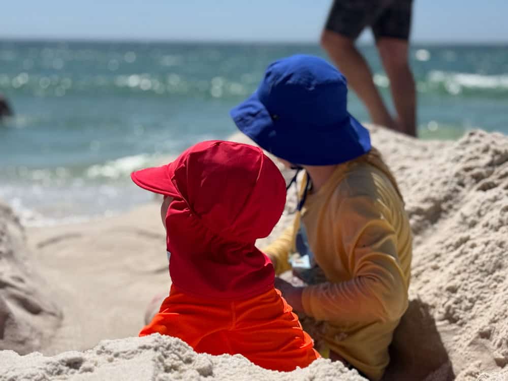 Two young children playing in sand at sunny beach
