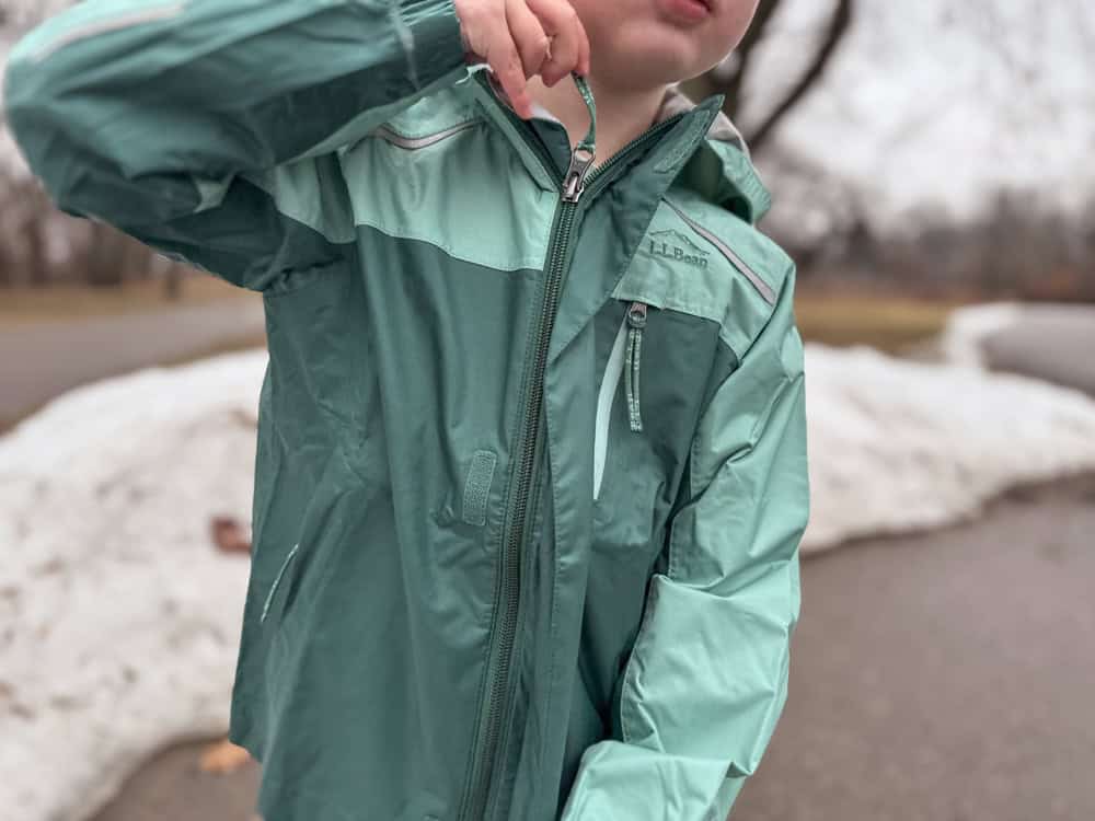 Child wearing teal L.L.Bean rain jacket outdoors in winter