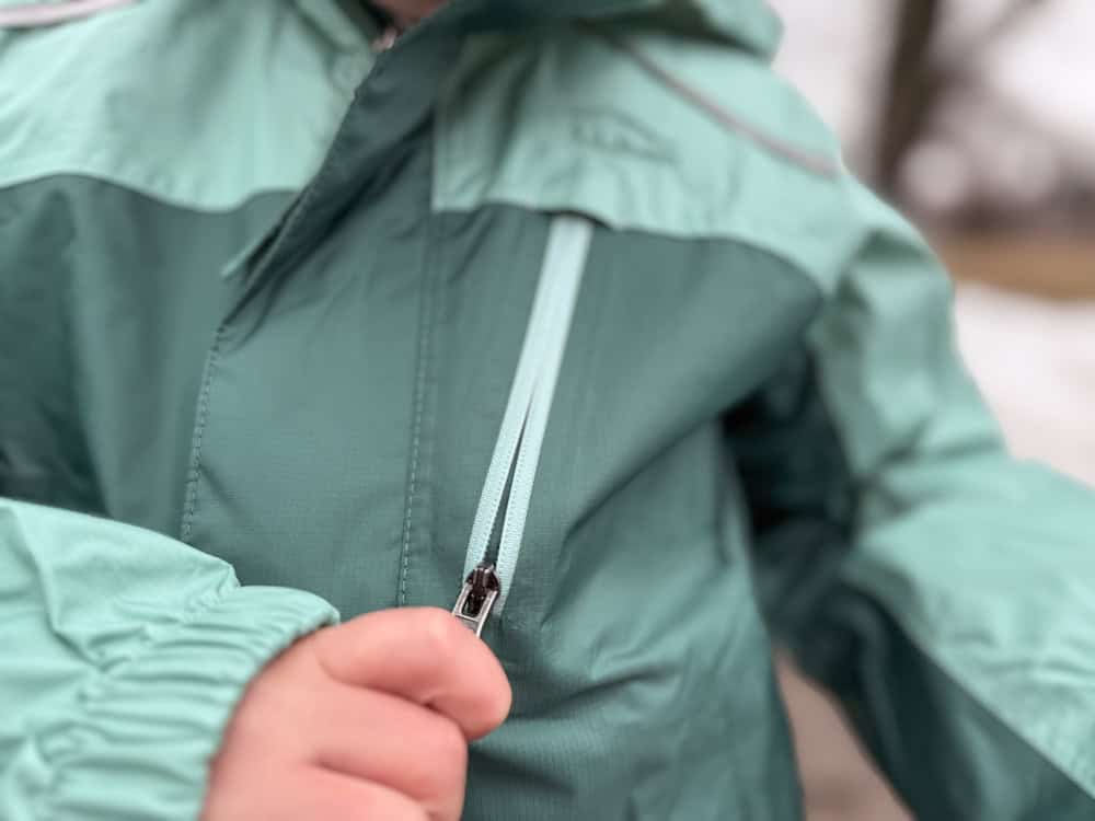 little boy wearing a green two toned jacket in the rain