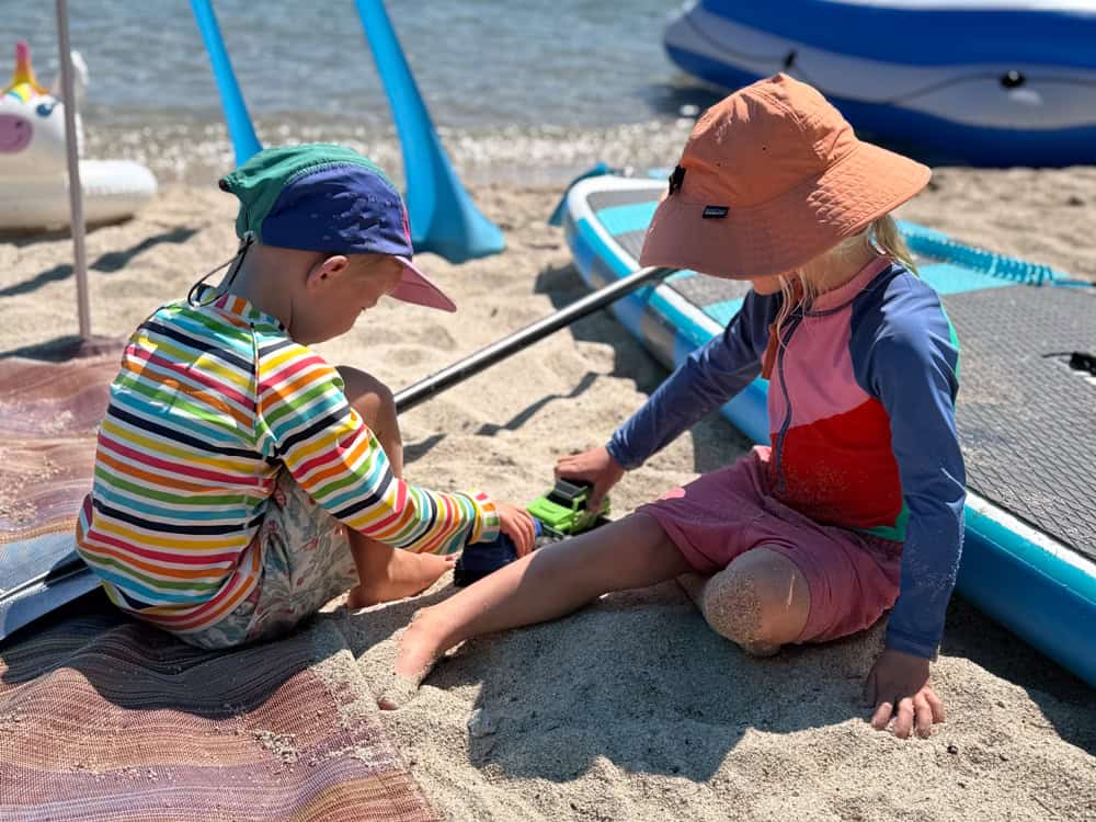 Two young children playing with toys on a sandy beach