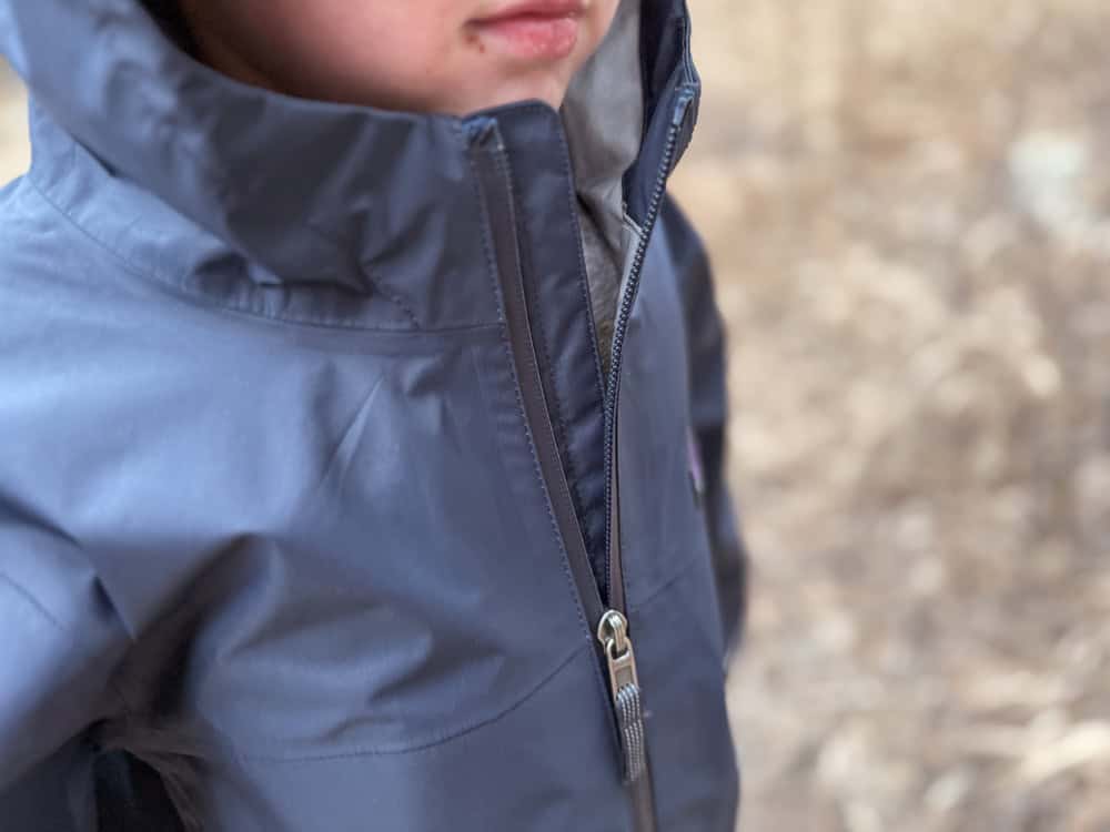 Young child wearing navy blue hooded rain jacket outdoors