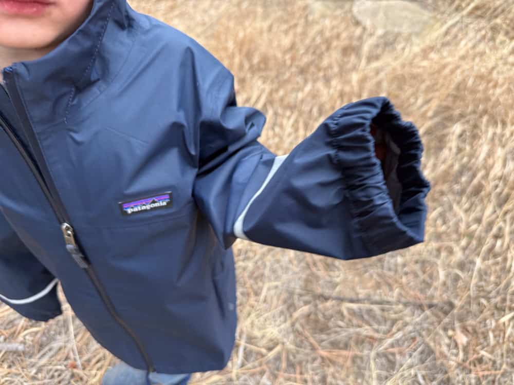 a boy holding up his rain jacket sleeve
