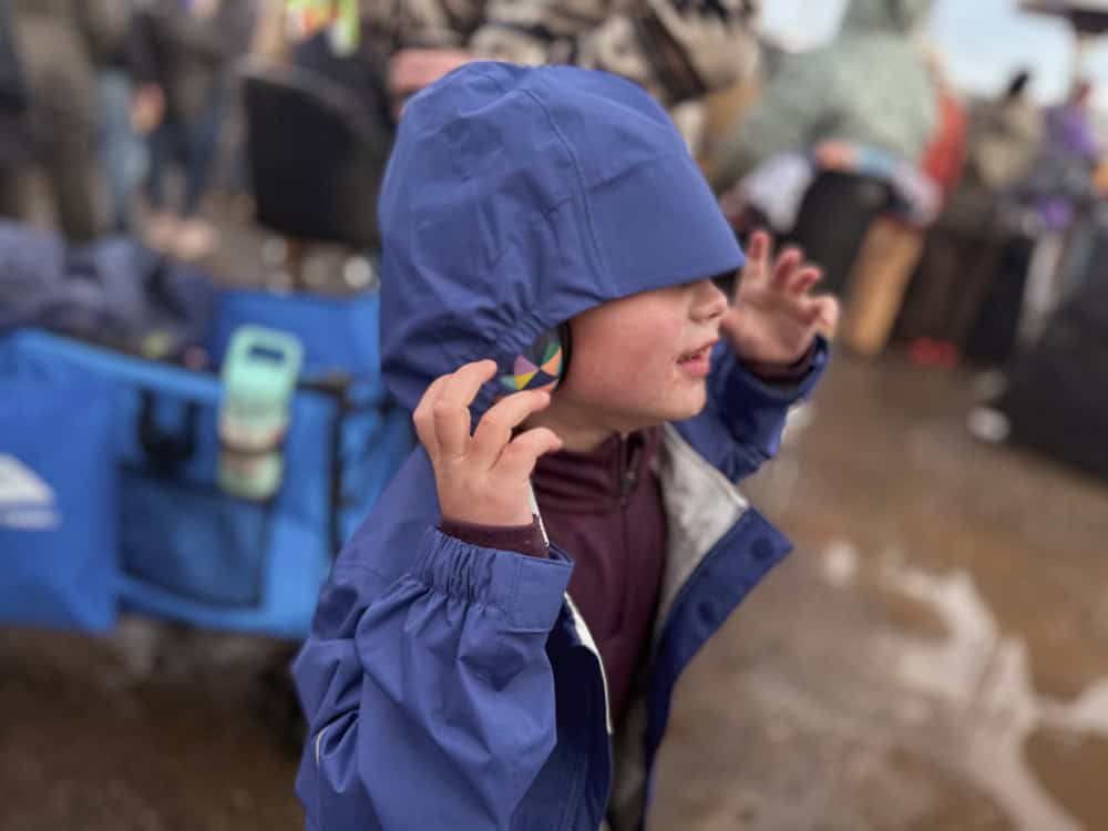 a little boy with a rain jacket hood over his head