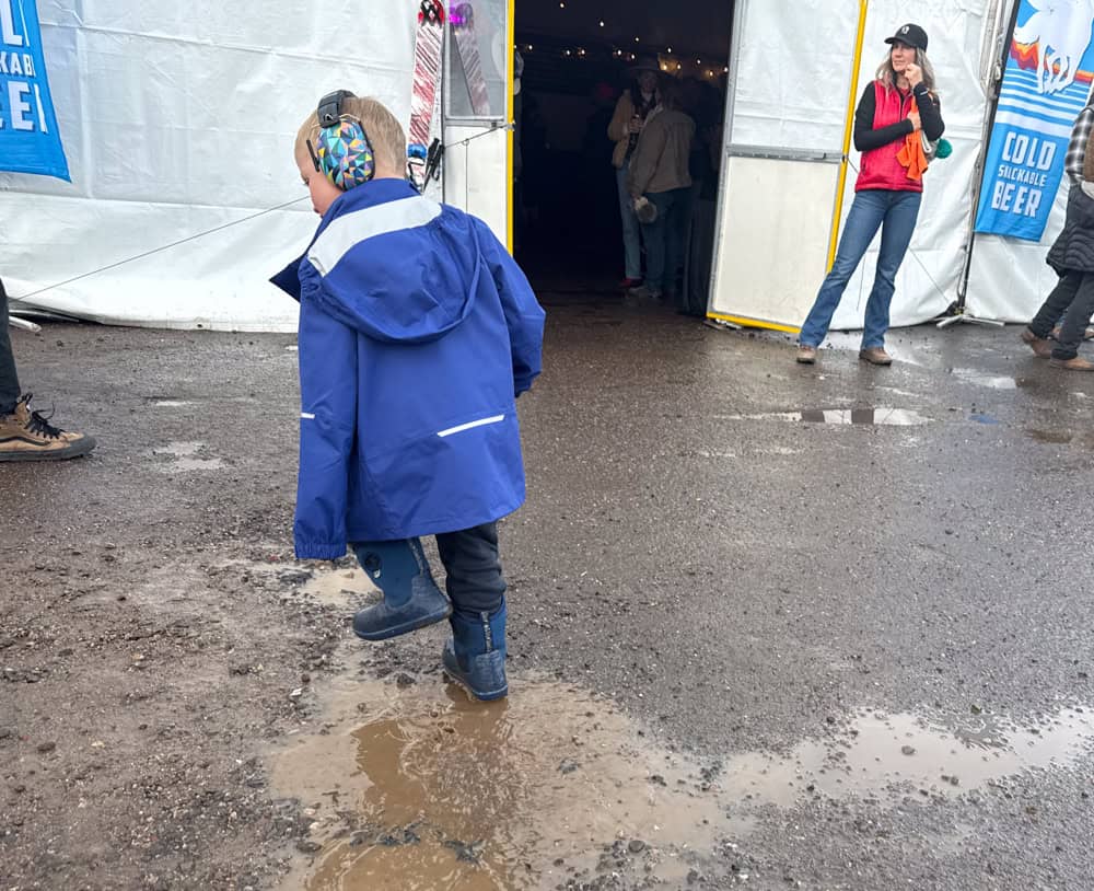 kit stands in puddle in rain in rain jacket