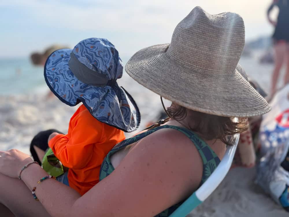 Mother and toddler wearing sun hats at the beach