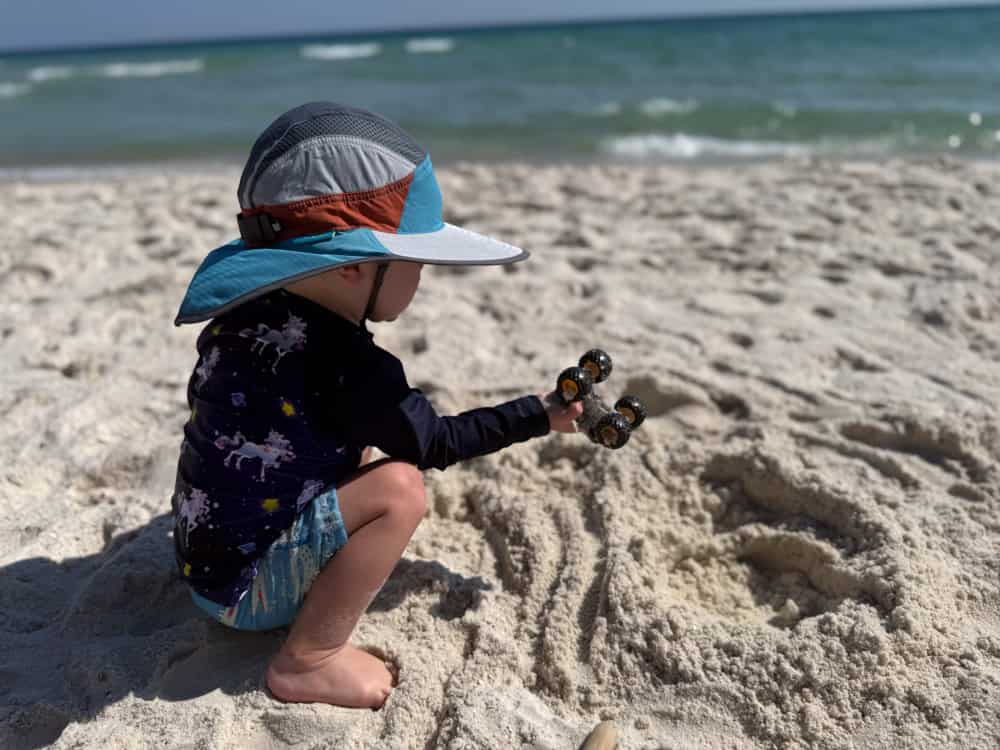 Toddler playing with toy car on sandy beach
