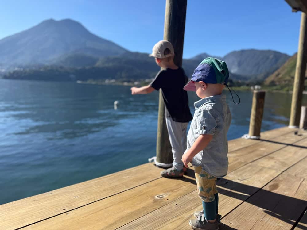 Two young children on a wooden dock overlooking mountain lake