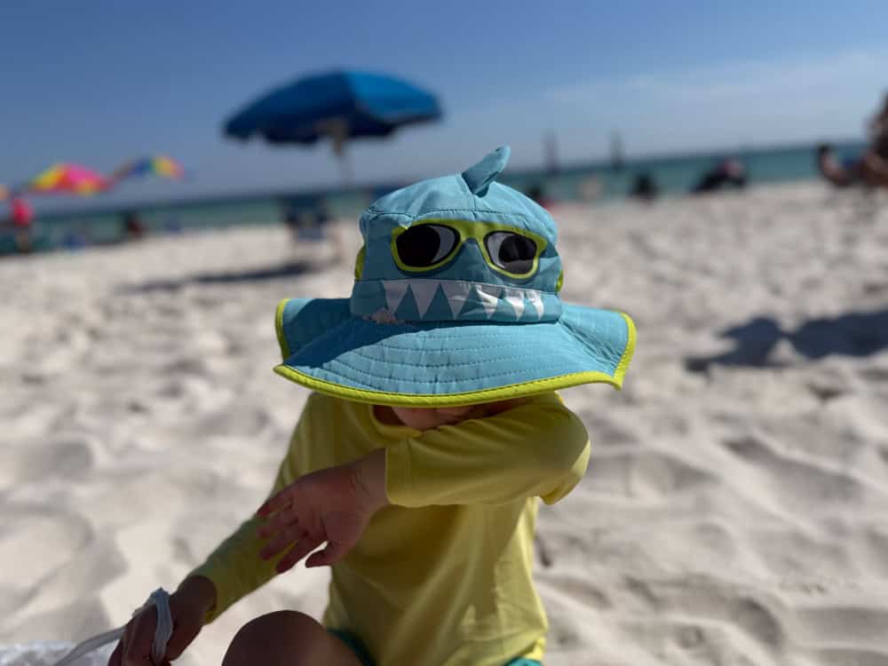 Toddler wearing shark bucket hat on sunny beach