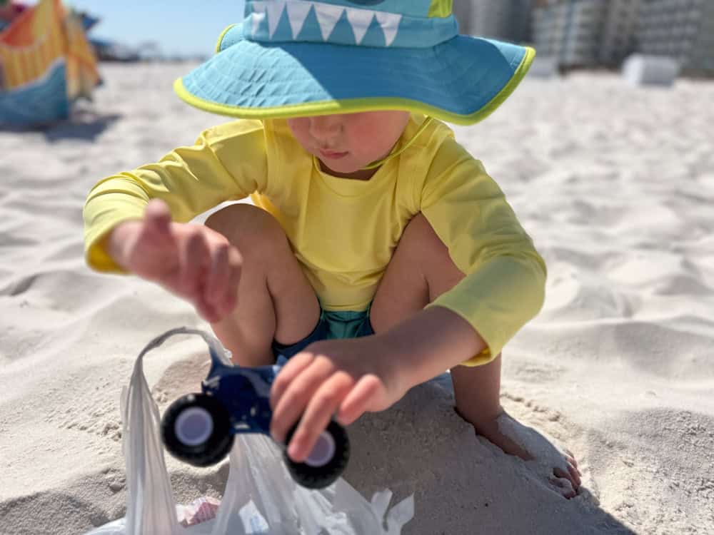 Young child playing with toy truck on sandy beach