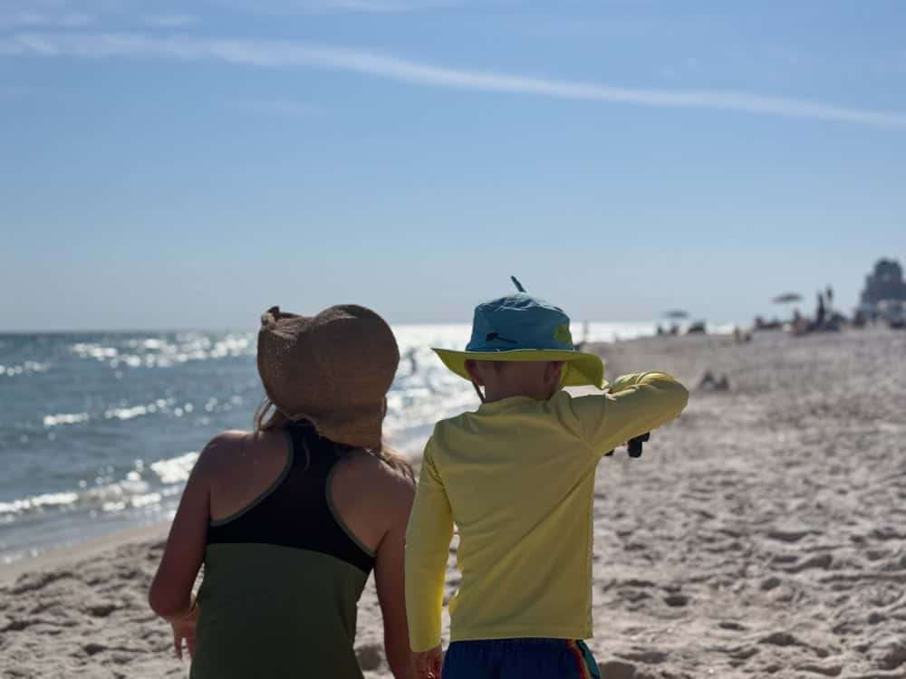 Two children wearing sun hats looking at ocean beach