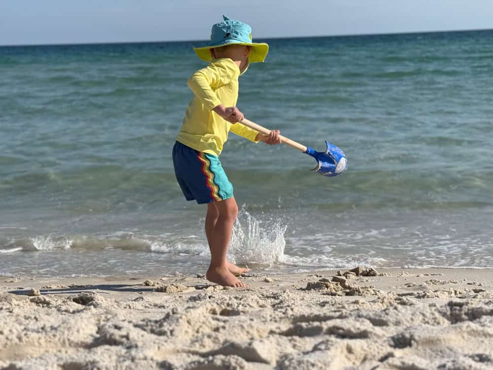 Young child playing with shovel at ocean shoreline