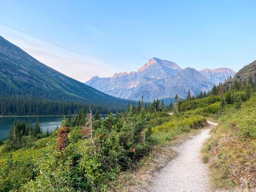 Scenic hiking trail beside mountain lake with alpine peaks
