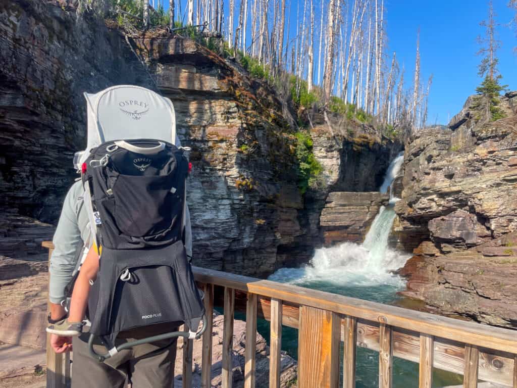 Hiker with Osprey Poco Plus child carrier at scenic waterfall