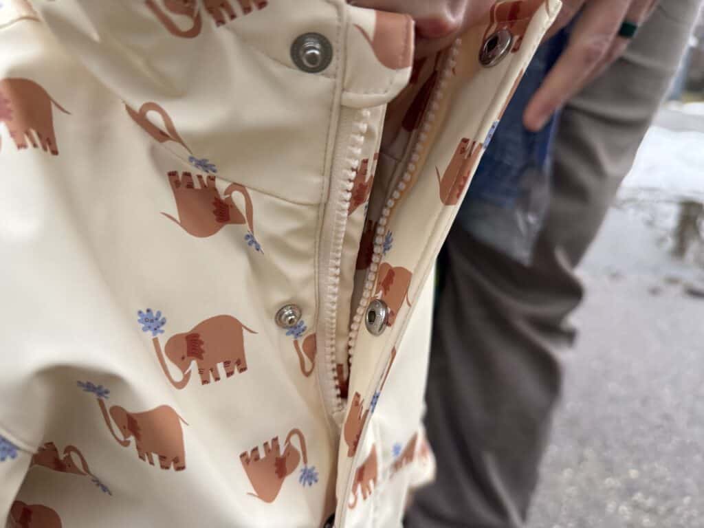 Close-up detail of Amazon Essentials Toddler Rain Jacket showing hidden zipper with snap guard closure