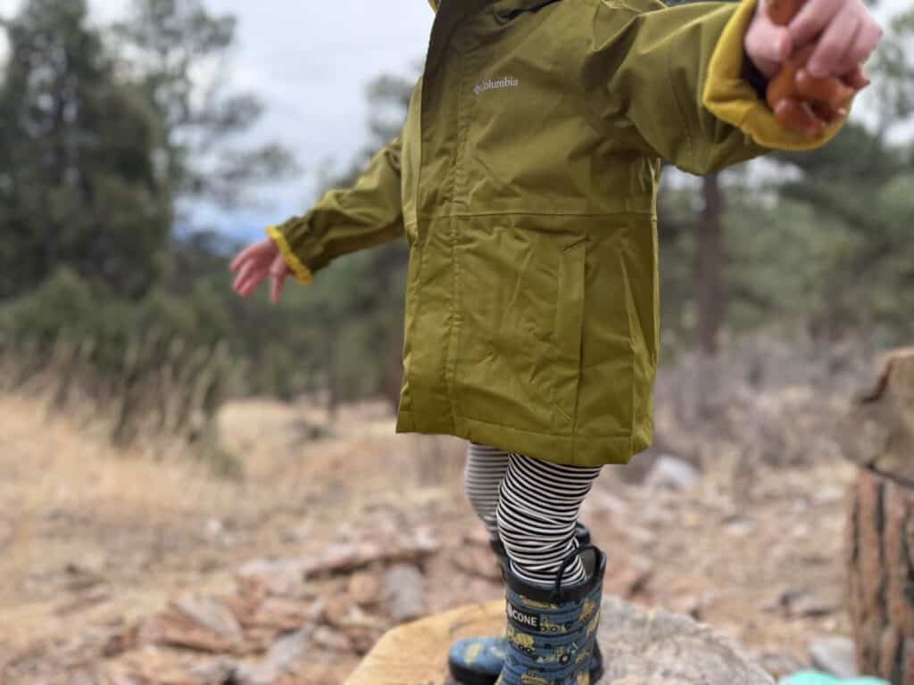 Toddler in Columbia Hikebound II Rain Jacket with arms spread wide showing front panel and Columbia logo
