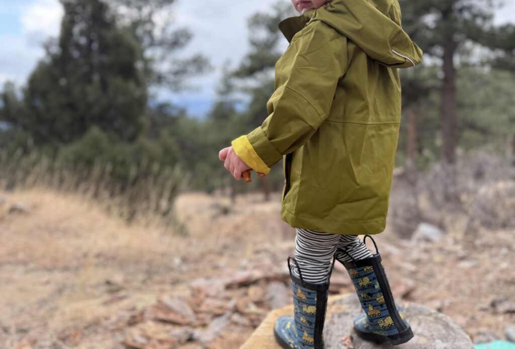 Side profile of toddler wearing Columbia Hikebound II Rain Jacket showing interior mesh cuff lining detail