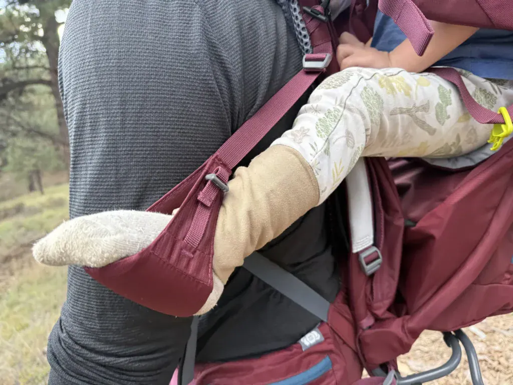 Close-up of a toddler's sock-covered foot resting in the foot loop of the Deuter Kid Comfort child carrier