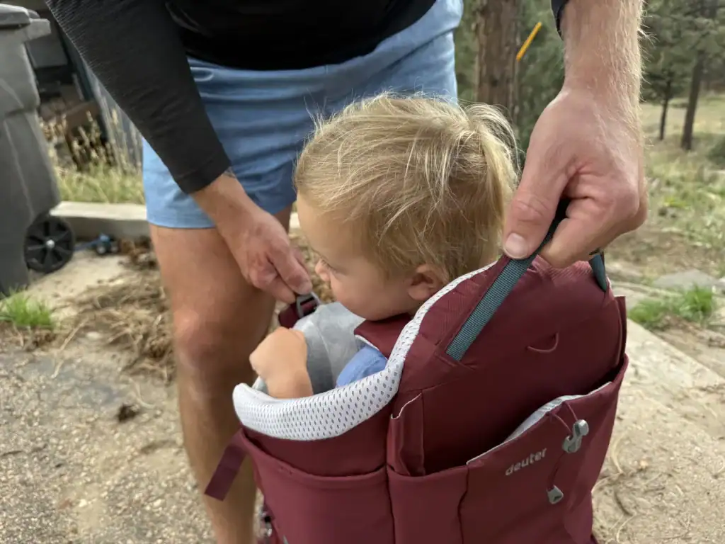 Toddler climbing into the Deuter Kid Comfort child carrier through the side opening