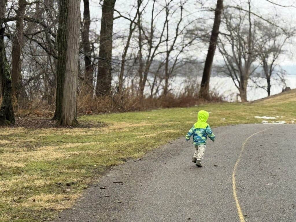 Toddler running down a path in the Eddie Bauer Toddler Rain Jacket