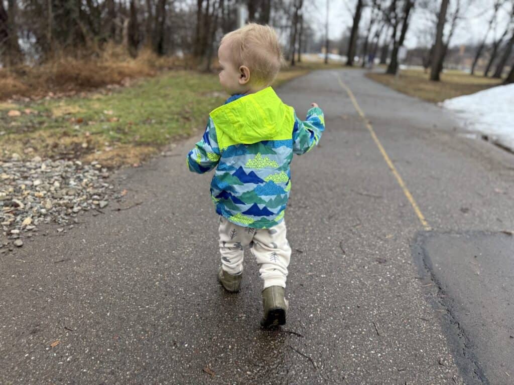 Back view of the mountain print on the Eddie Bauer Toddler Rain Jacket on a toddler walking