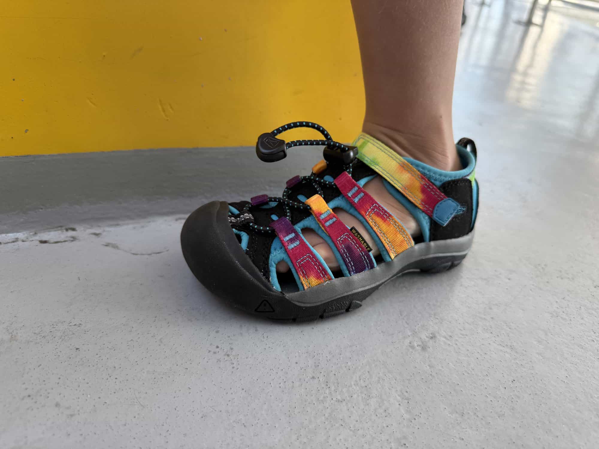 Side view of a tie-dye KEEN Newport H2 kids sandal with bungee lace and rubber toe cap