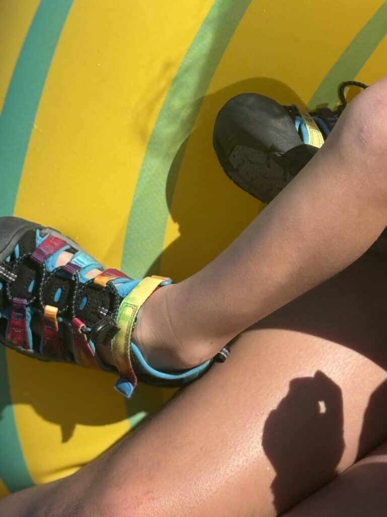 Kid feet in tie-dye KEEN Newport H2 sandals on a yellow water park float in Destin, Florida