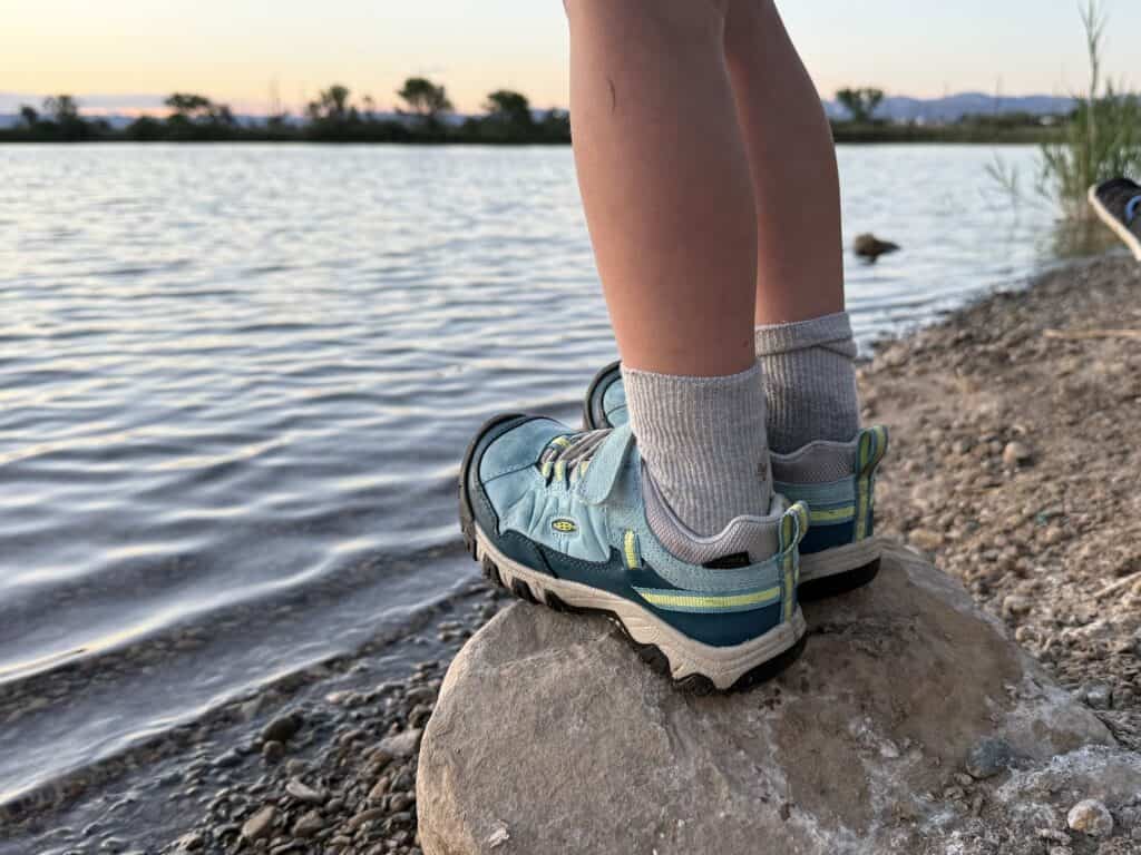 Kid standing on a rock at the water edge in KEEN Targhee IV Low Waterproof shoes