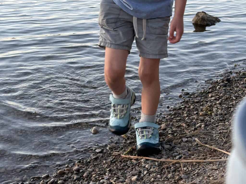 Kid walking out of a lake onto gravel in KEEN Targhee IV Low Waterproof shoes