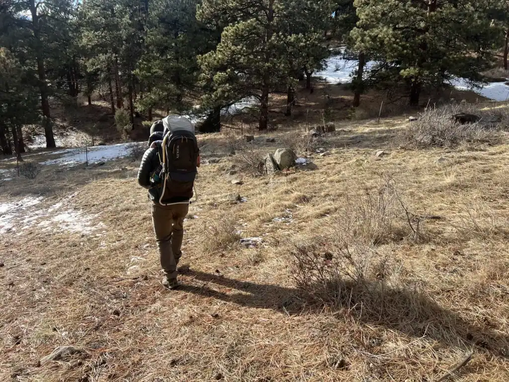 Adult walking away on a grassy trail carrying the Kelty Journey PerfectFIT Elite child carrier