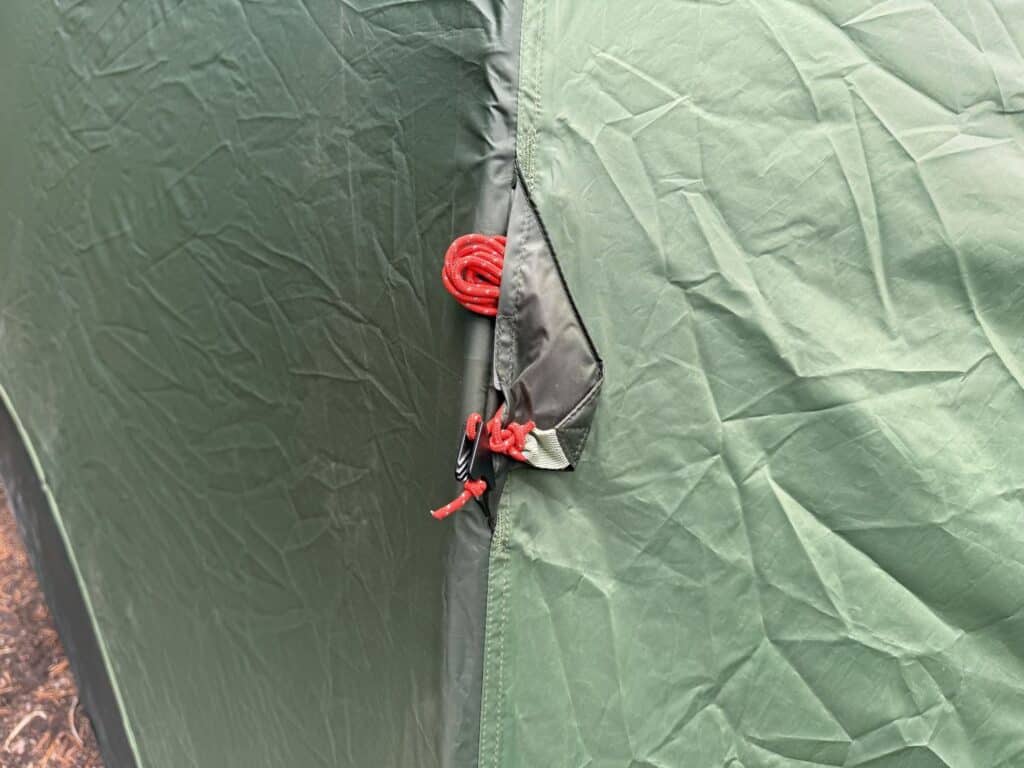 Red guyline tucked into a small stash pocket on the green rainfly of the Kelty Wireless 6