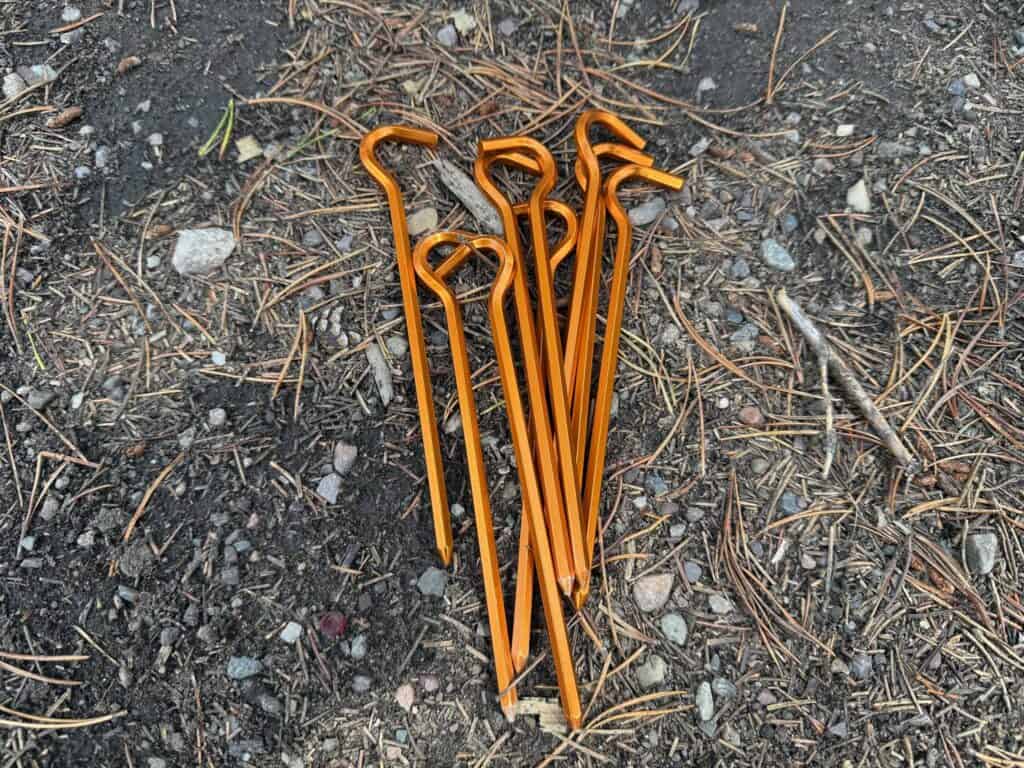 Orange tent stakes from the Kelty Wireless 6 laid on the ground