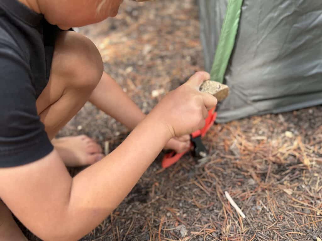 Child pushing a tent stake into the color-coded corner of the Kelty Wireless 6