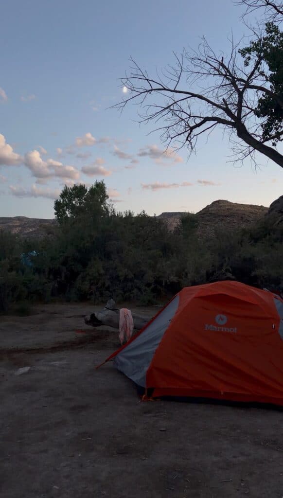 Marmot Tungsten tent with its orange rainfly at a campsite at dusk