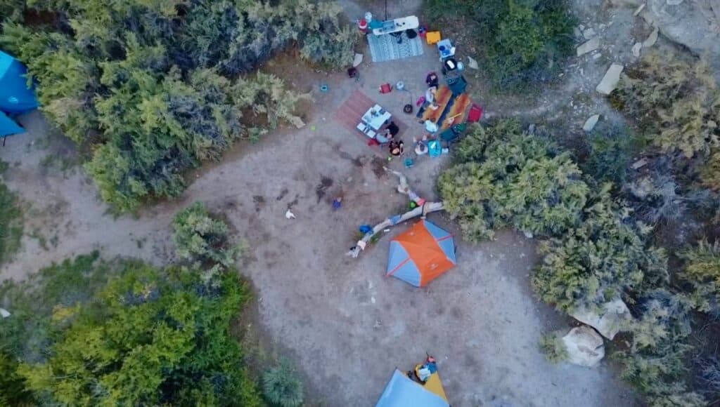 Overhead view of a riverside camp with the orange Marmot Tungsten among shrubs