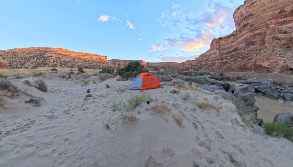 Marmot Tungsten tent pitched on a sandy bench in a wide red-rock canyon