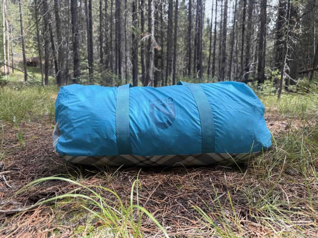 NEMO Aurora Highrise 6 packed in its blue duffel carry bag on a forest floor