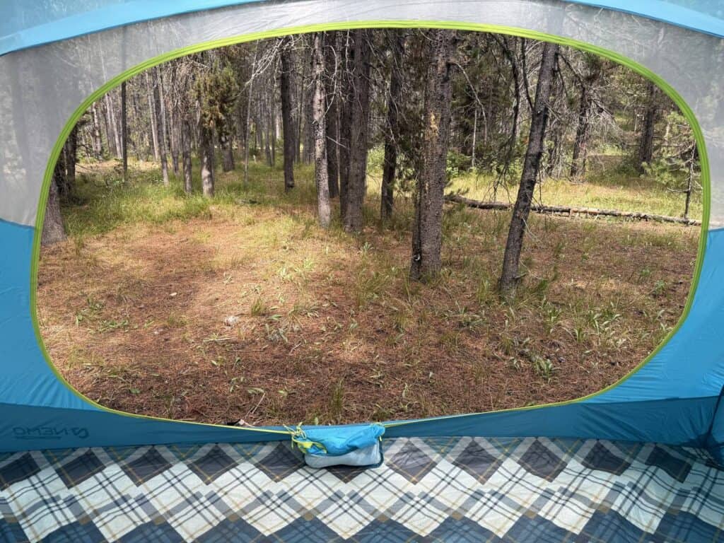 Wide view out the large front door of the NEMO Aurora Highrise 6 toward a forest campsite