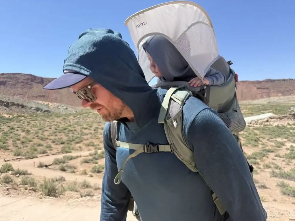 Adult hiking a desert trail with the Osprey Poco Premium child carrier sunshade up