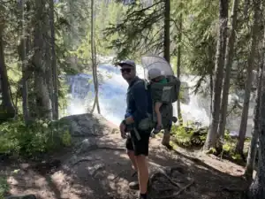 Dad standing in front of Redfish Lake Creek Falls wearing the Osprey Poco Premium child carrier