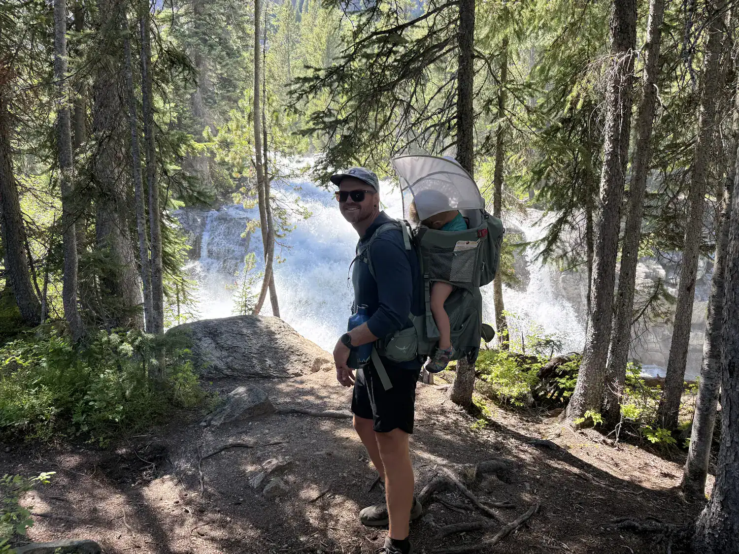 Dad standing in front of Redfish Lake Creek Falls wearing the Osprey Poco Premium child carrier
