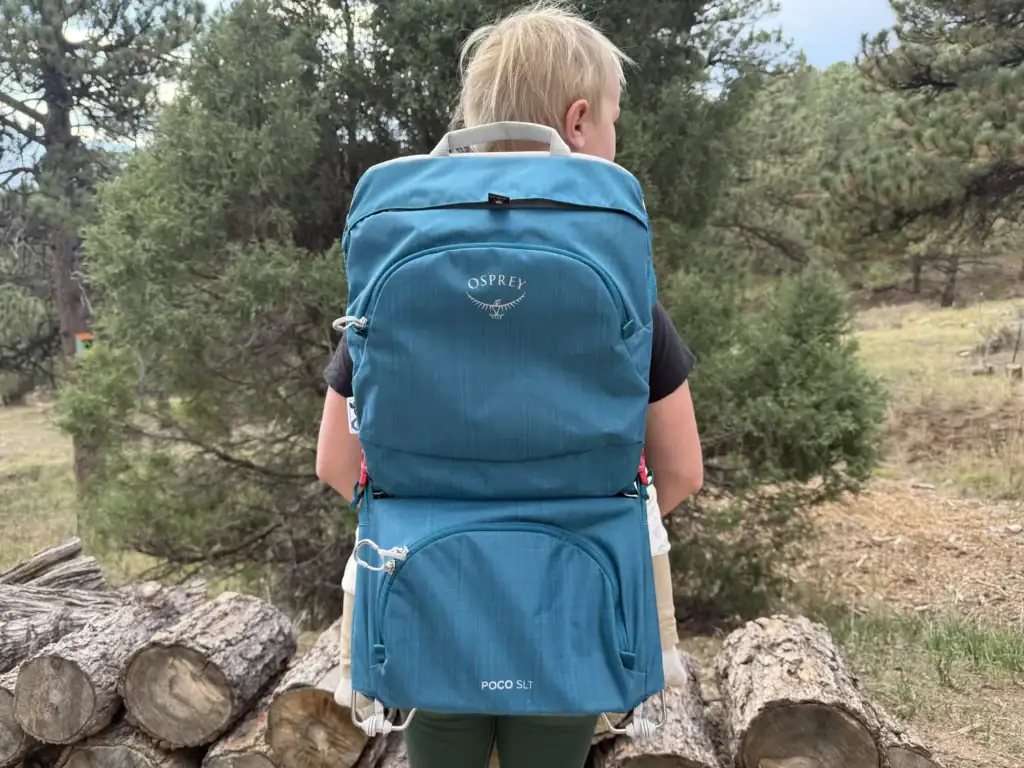 Rear view of an adult wearing the Osprey Poco SLT child carrier with a toddler riding
