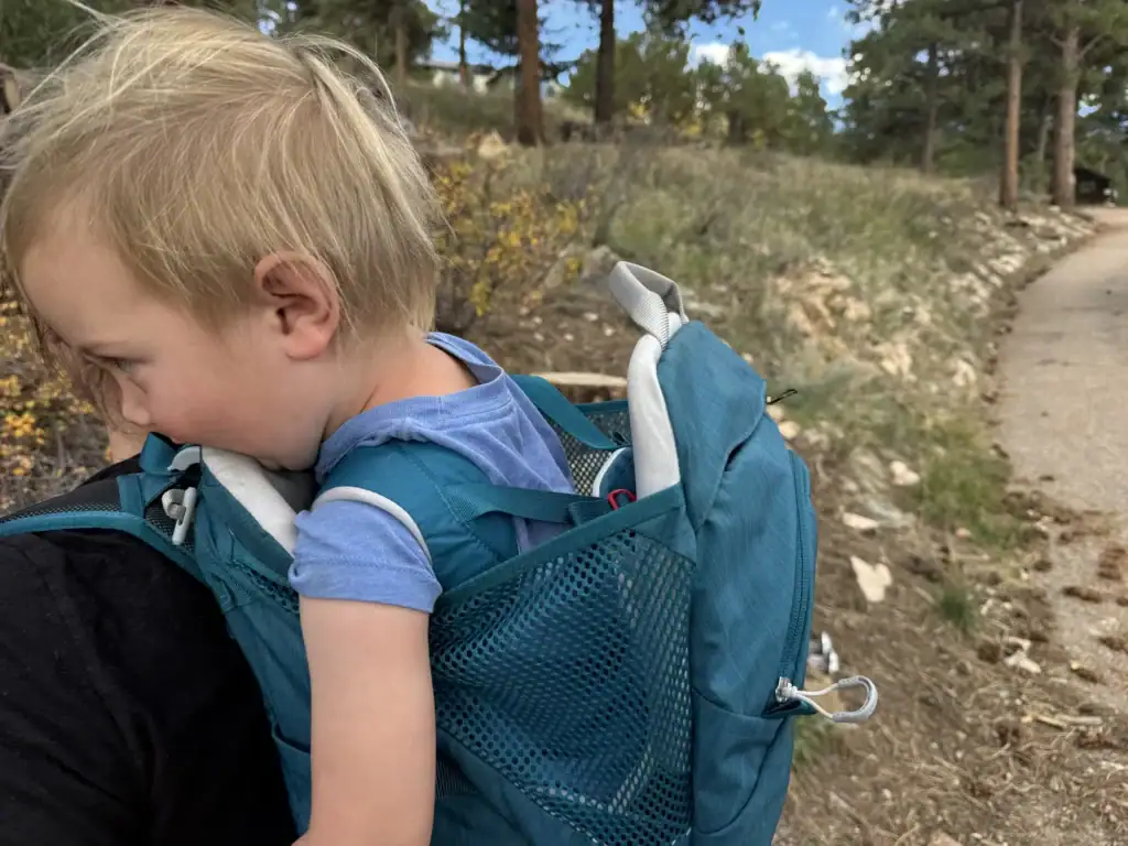 Toddler riding in the Osprey Poco SLT child carrier on a pine forest trail