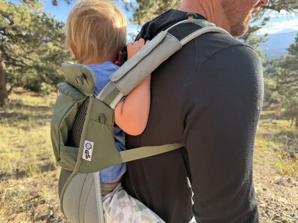 Close-up of a toddler riding on an adult's back in the Osprey Poco Soft child carrier